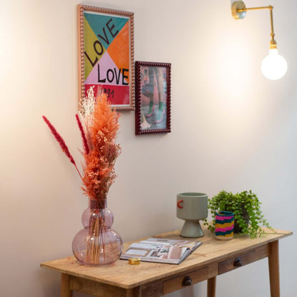 Small wooden table with decorative items against a wall with framed art