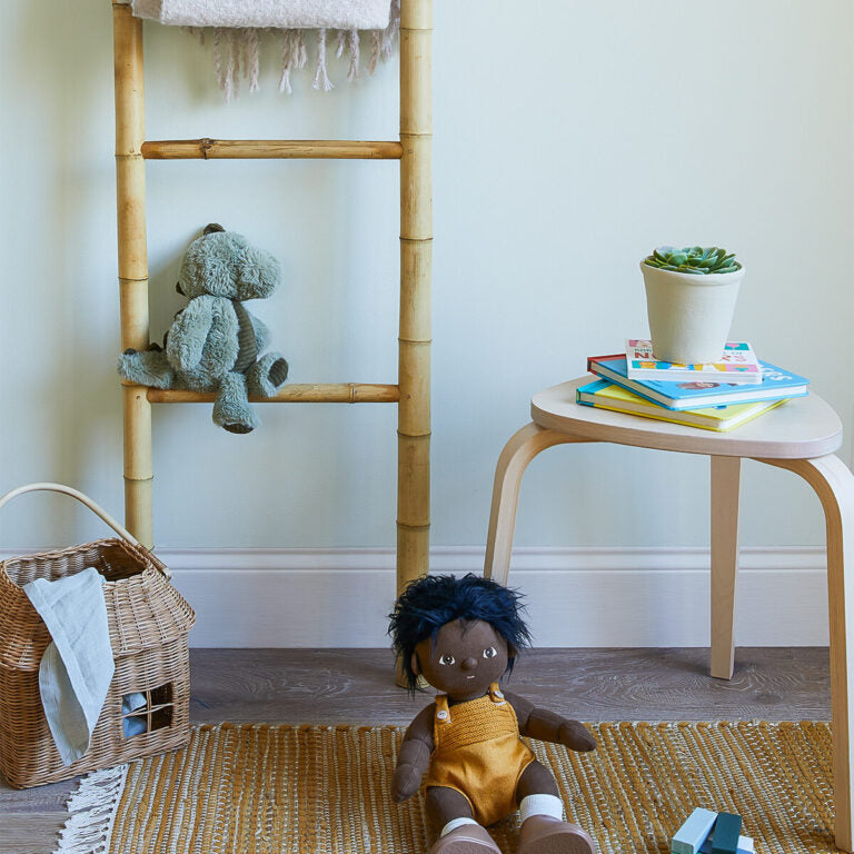 Child's room with a doll, teddy bear, and books on a stool.
