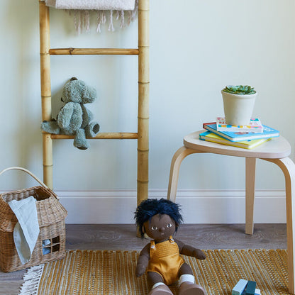 Child's room with a doll, teddy bear, and books on a stool.