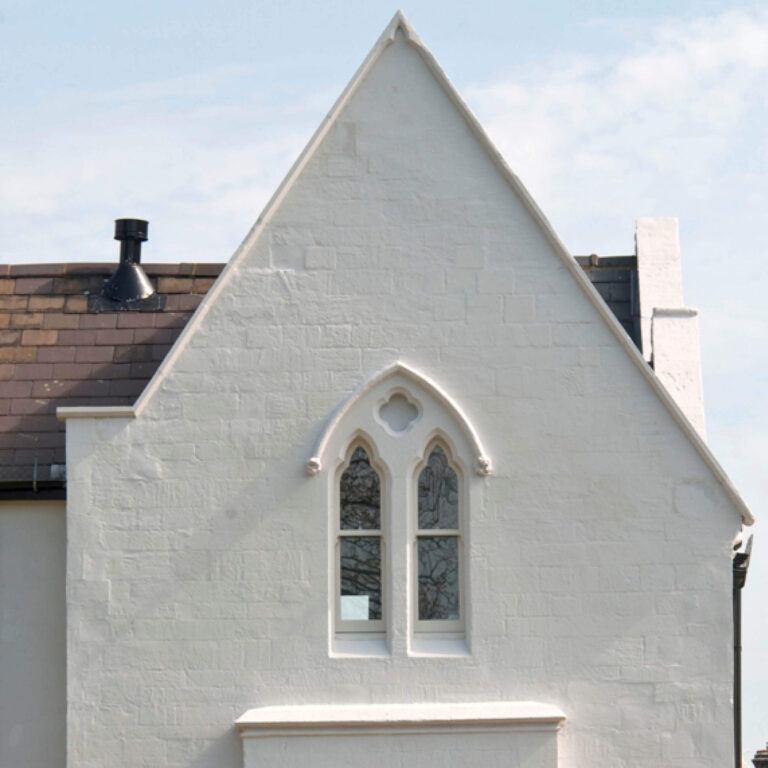 Gothic-style window on a white building with a clear blue sky.