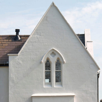 Gothic-style window on a white building with a clear blue sky.