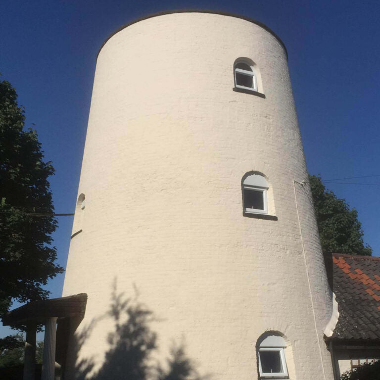 Tall cylindrical building with windows against a clear blue sky