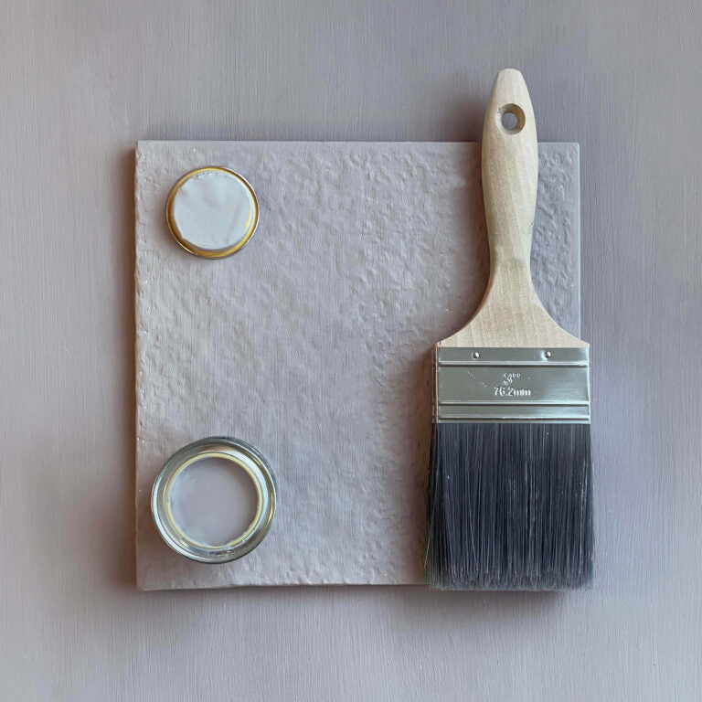 Paintbrush with a container of paint on a textured surface