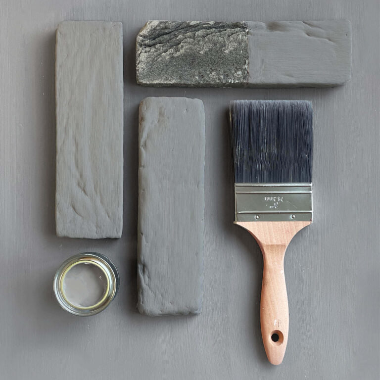 Paintbrush with gray paint and sample blocks on a gray background