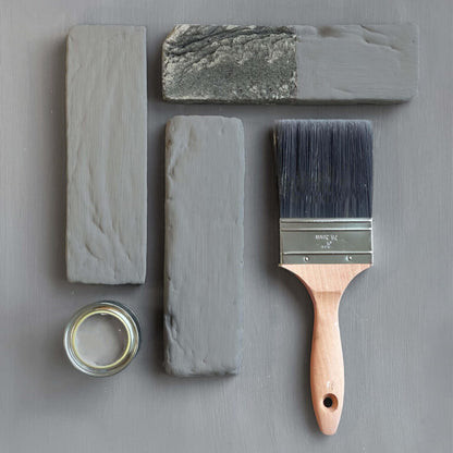 Paintbrush with gray paint and sample blocks on a gray background