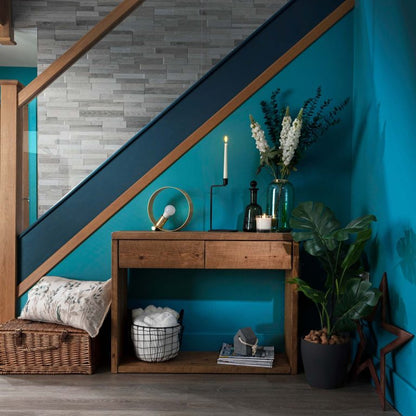 Nestled staircase with wooden console table against a blue wall, featuring decorative items.