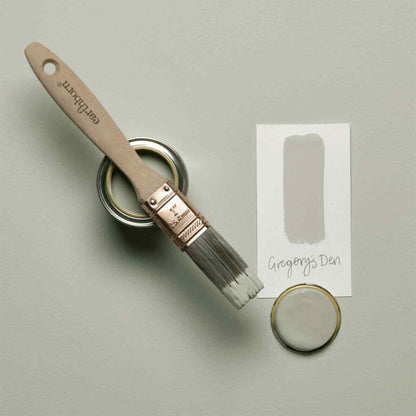 Paintbrush and paint can with color swatch labeled 'Gregory's Den' on a light gray background