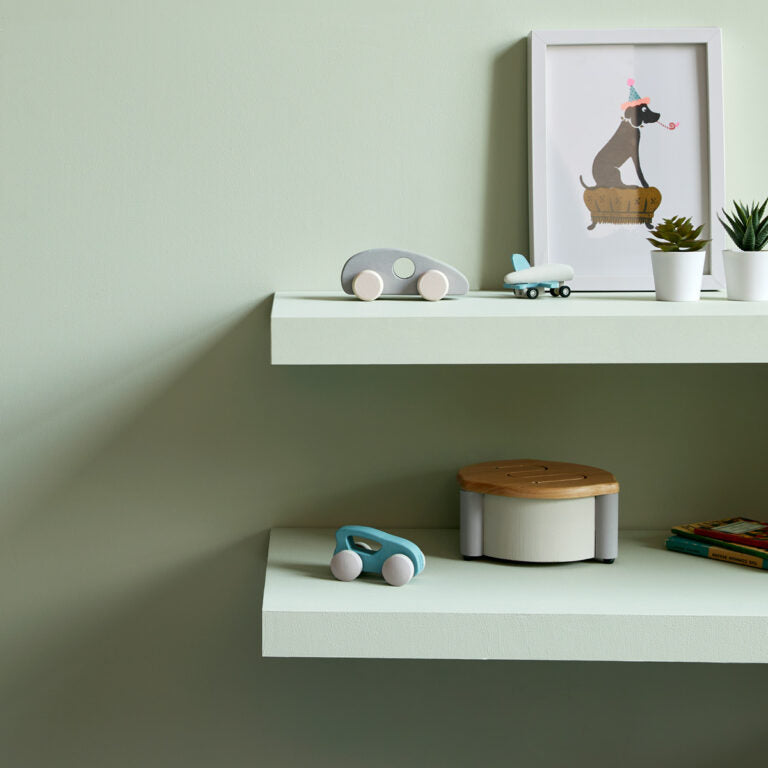White shelves with toys and a framed picture on a light green wall