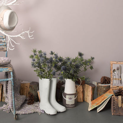 White rain boots with decorative plants and rustic decor items on a gray surface.
