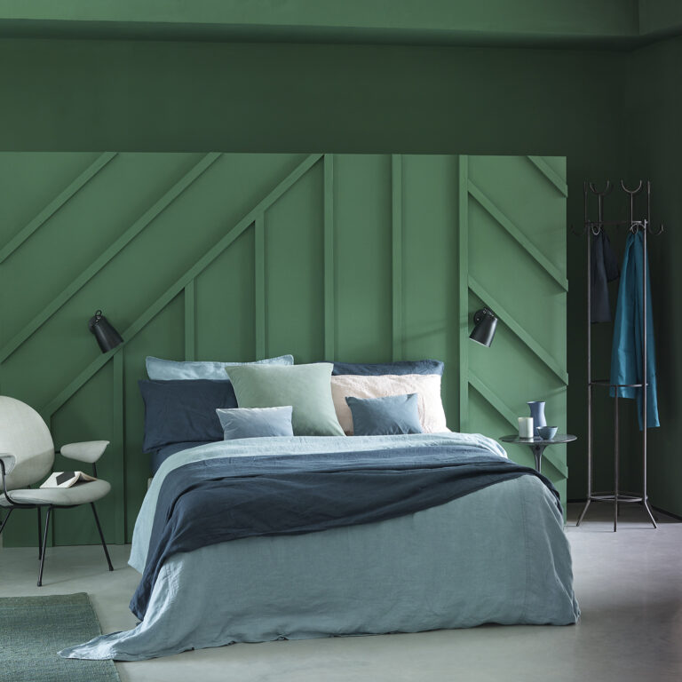 Modern bedroom with green wall and bed with blue and gray bedding