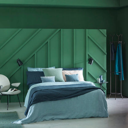 Modern bedroom with green wall and bed with blue and gray bedding