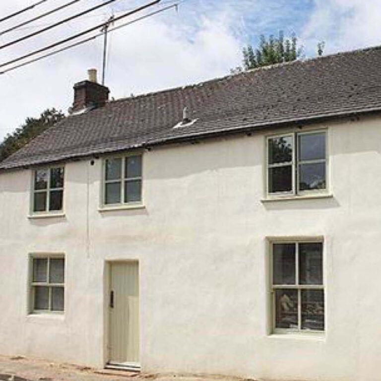 White terraced house with a gray roof and windows on a clear day.