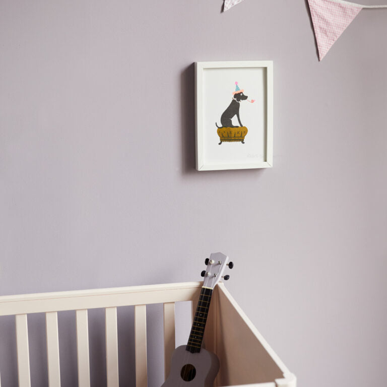 Framed artwork of a dog on a bed above a white crib with a guitar in a nursery.