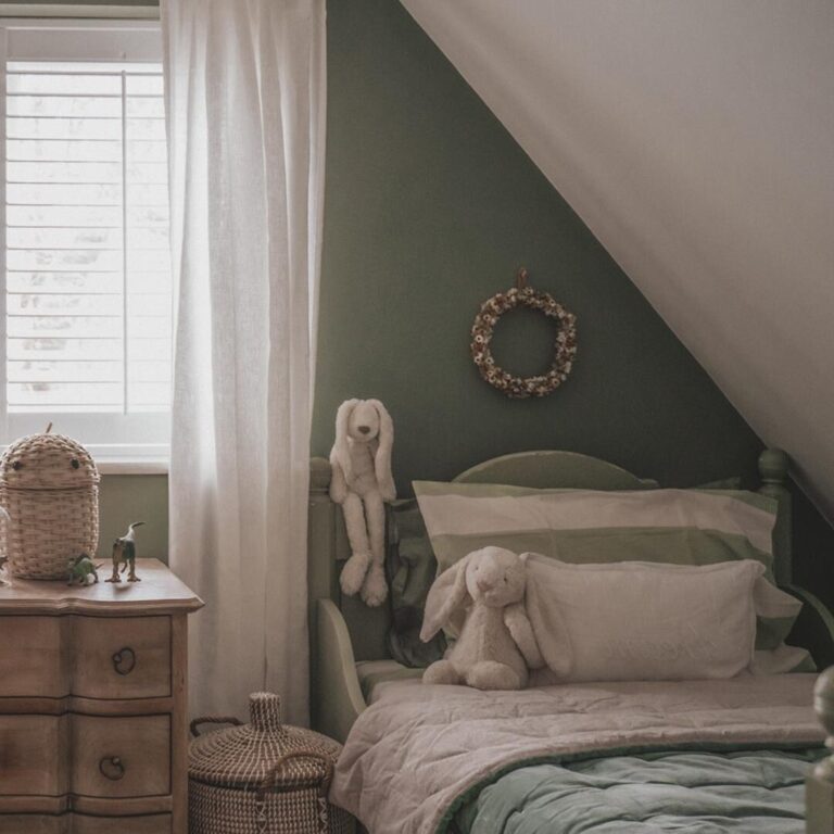 Children's bedroom with green walls, a bed with plush toys, and a wooden nightstand.