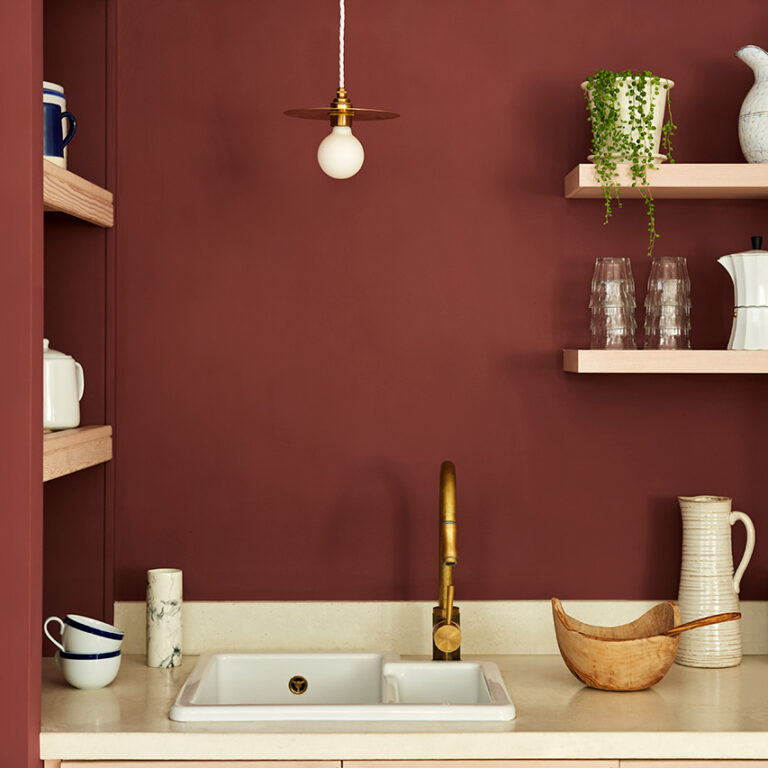 Kitchen with red walls, wooden shelves, and a white sink.