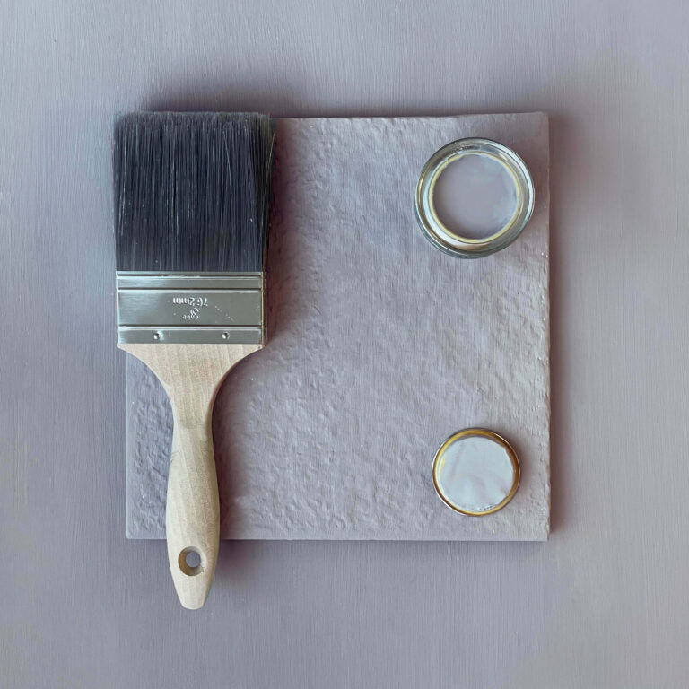Paintbrush and two paint samples on a textured surface