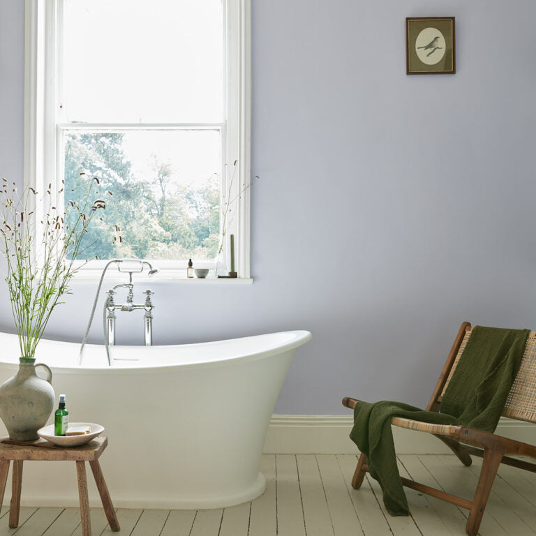 Bathroom with freestanding bathtub, wooden chair, and window view