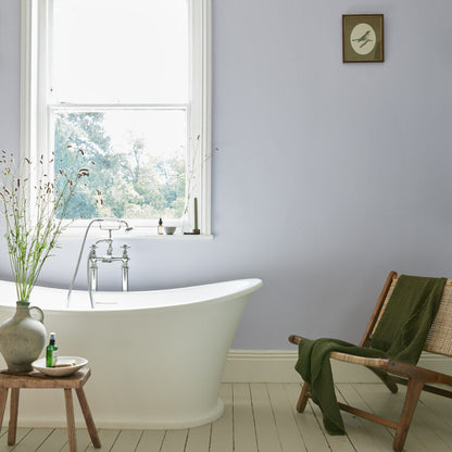Bathroom with freestanding bathtub, wooden chair, and window view