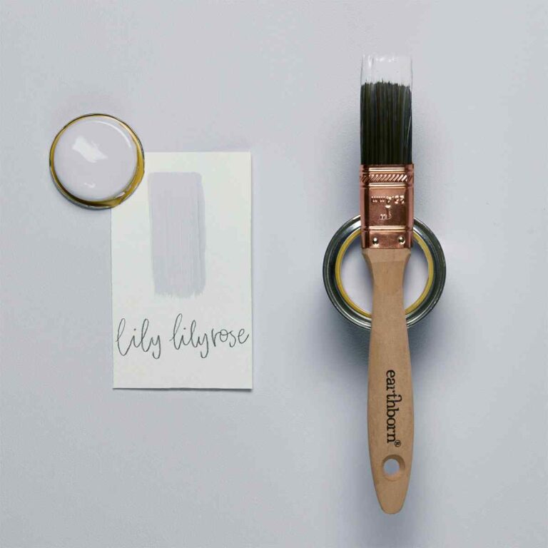 Paintbrush with wooden handle and metal bristles, surrounded by paint and a card on a gray background.