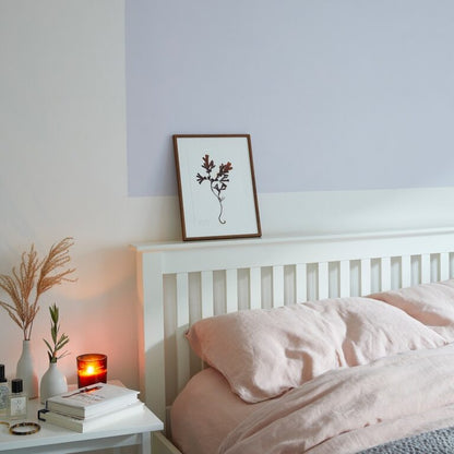 Bedroom with white bed, pink bedding, and a small table with decor items.