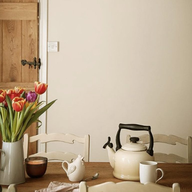 Tea set with a teapot, cups, and flowers on a wooden table.