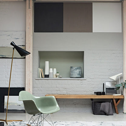 Modern interior with a green chair, wooden table, and decorative items against a white brick wall.