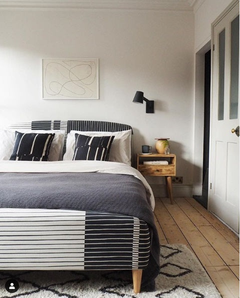 Modern bedroom with a bed, nightstand, and abstract wall art.