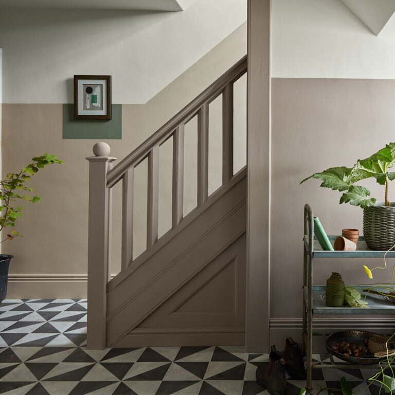 Staircase with wooden handrail and patterned floor in a home interior.