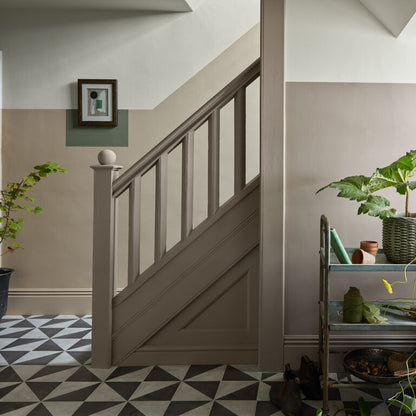 Staircase with wooden handrail and patterned floor in a home interior.