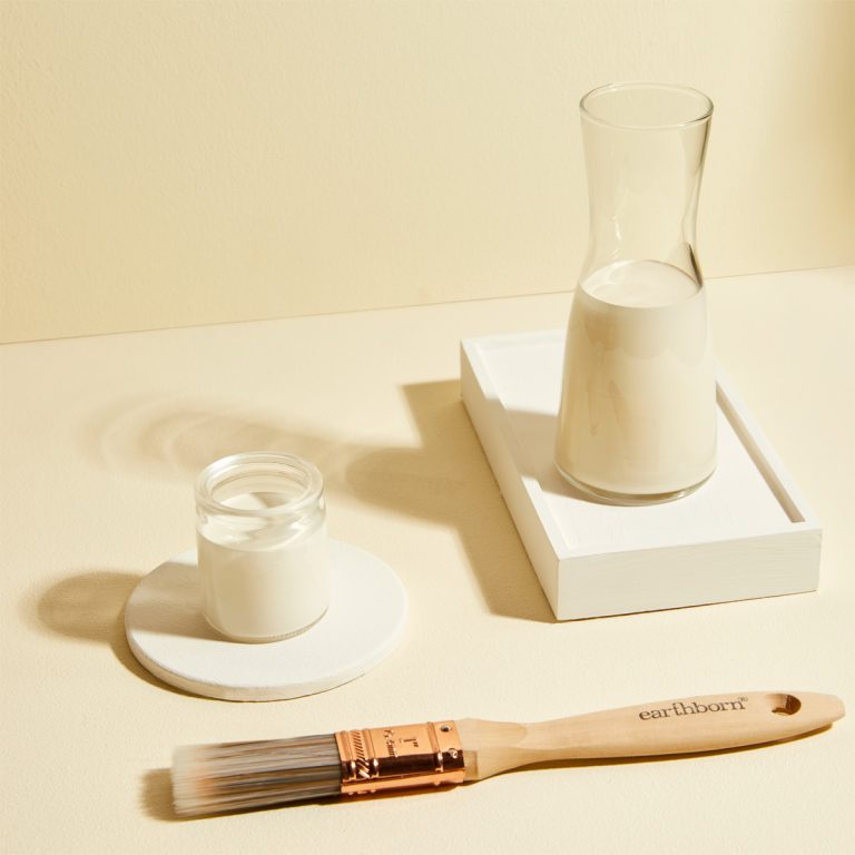 Candle, glass, and brush on a beige surface with a soft focus background