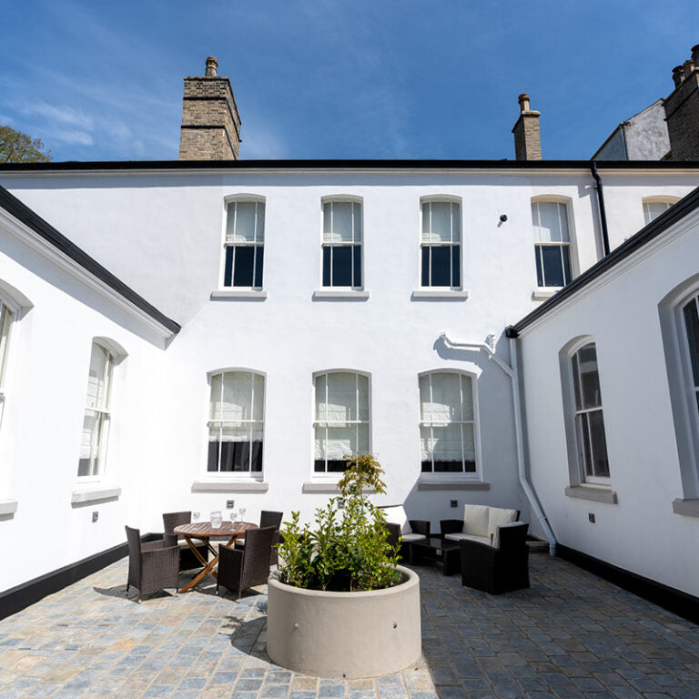 White building with a patio area featuring outdoor furniture and plants.