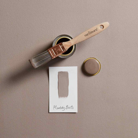 Paintbrush and paint container with a swatch on a beige background