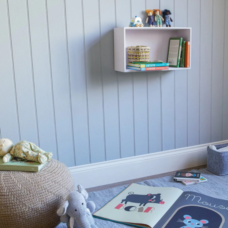 Children's room with a white shelf against a light blue paneled wall, books, and toys.