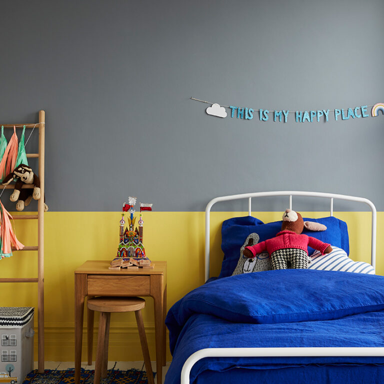 Children's bedroom with a bed, nightstand, and wall decoration.