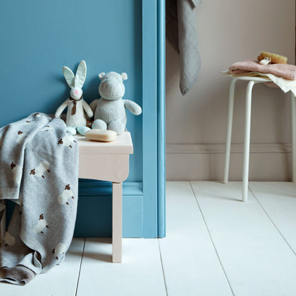 Children's room with plush toys and a blanket on a small table against a blue wall.