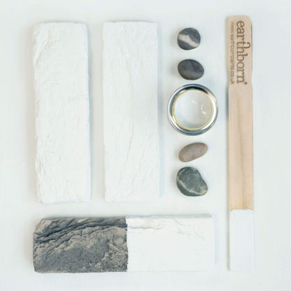 Collection of natural items including a soap bar, stones, and a candle on a white background with 'earthborn' branding.