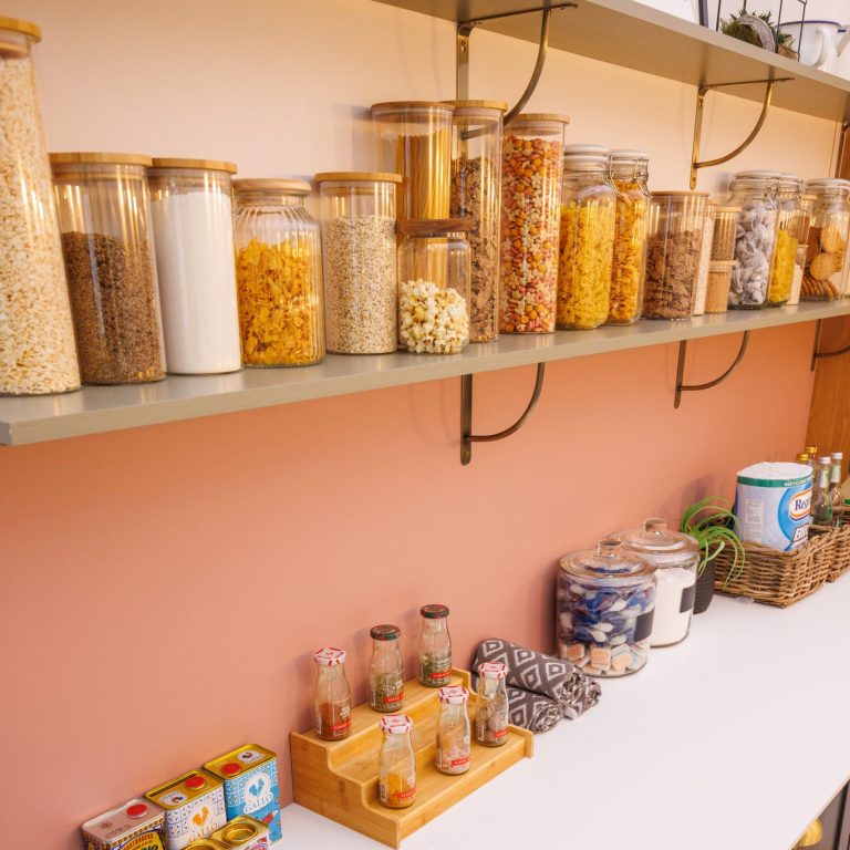 Shelves with various jars of snacks against a pink wall.
