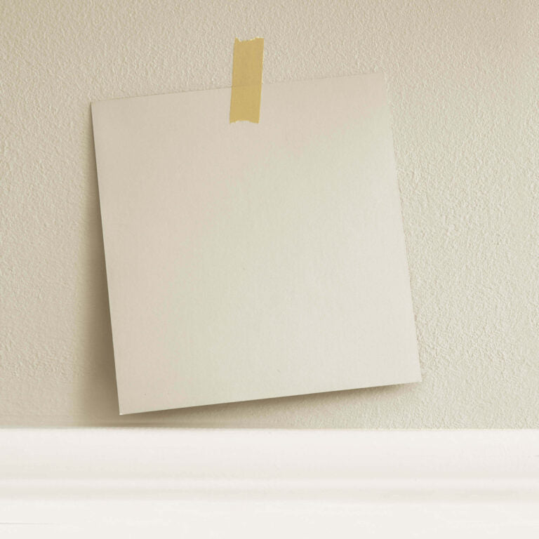 Beige envelope with gold tape on a textured beige wall