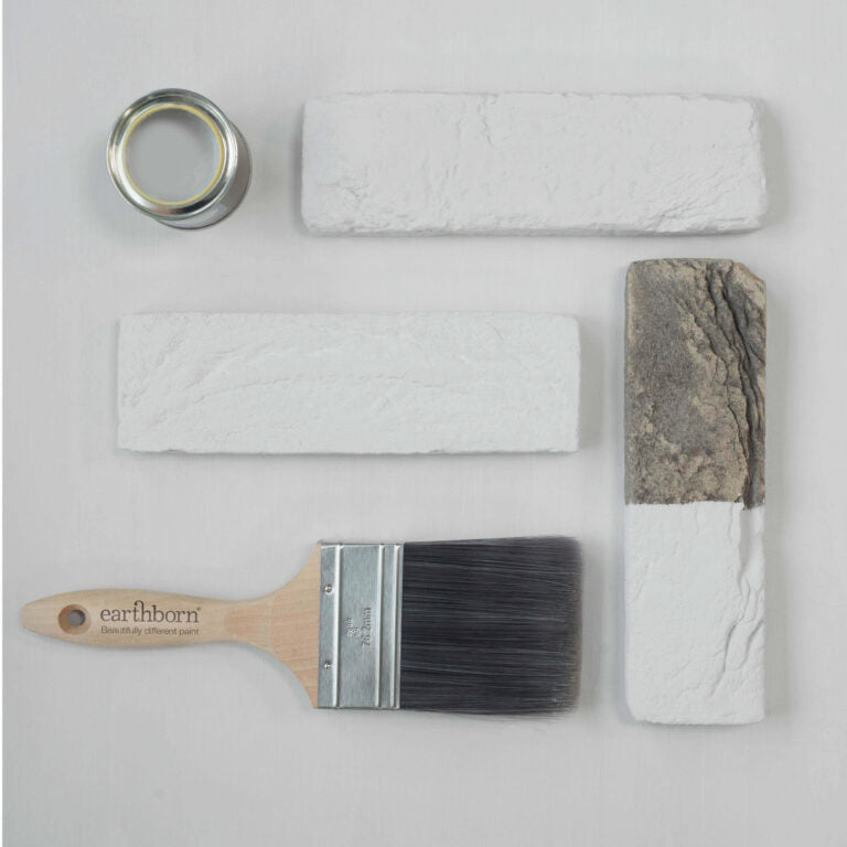 Paintbrush, painter's tape, and textured paint samples on a light gray background