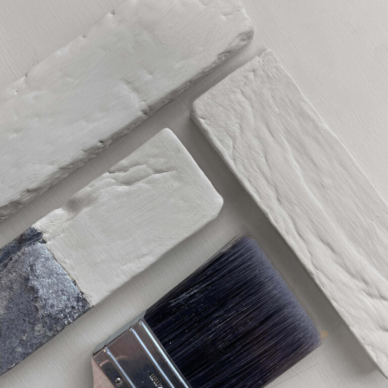 Close-up of a paintbrush with gray paint on a textured gray surface