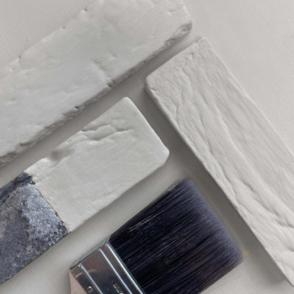 Close-up of a paintbrush with gray paint on a textured gray surface