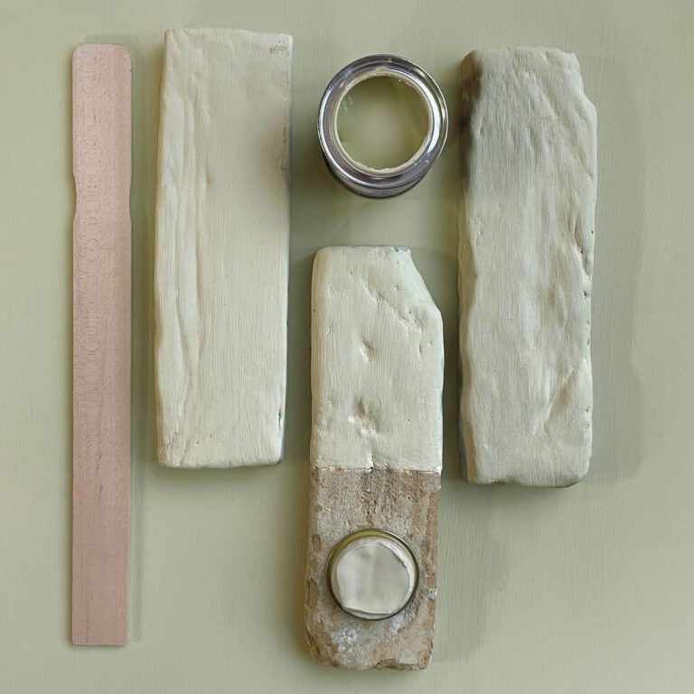 Wooden planks with different finishes and a can of paint on a light green background