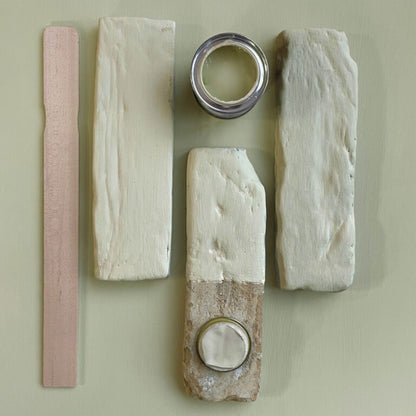 Wooden planks with different finishes and a can of paint on a light green background