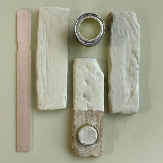 Wooden planks with different finishes and a can of paint on a light green background