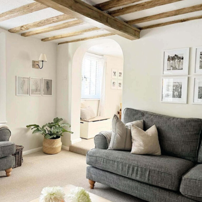 Living room with gray sofa, wooden beams, and framed pictures.