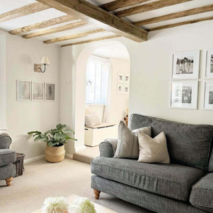 Living room with gray sofa, wooden beams, and framed pictures.
