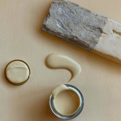 Close-up of a can of white paint with a swatch on a beige surface.