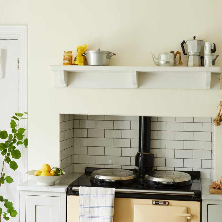 Small kitchen with white shelves, stove, and tiled wall.