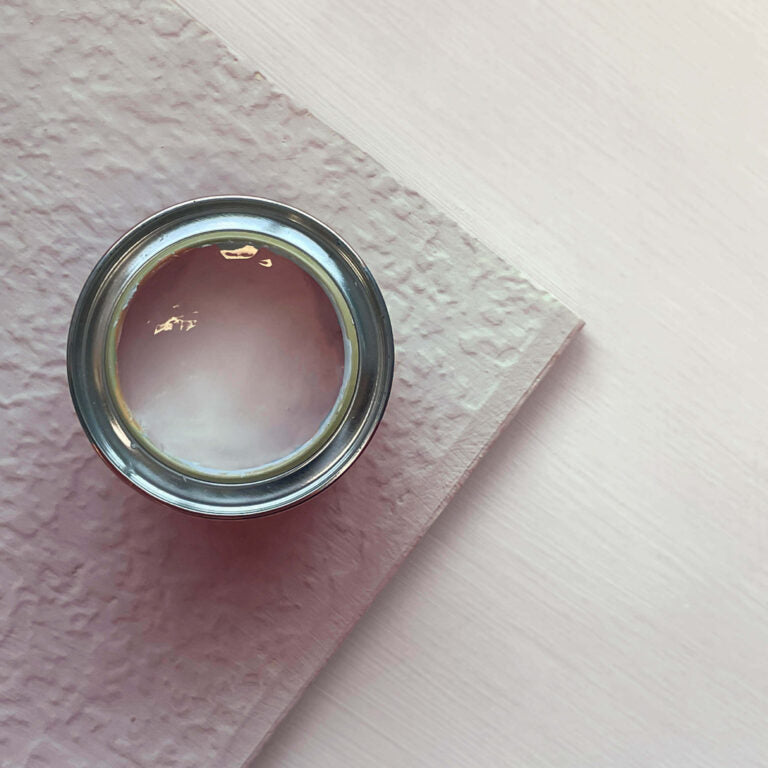 Close-up of a can of pink paint on a textured surface