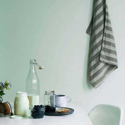 Table setting with a bottle, cup, and plate against a light green wall.